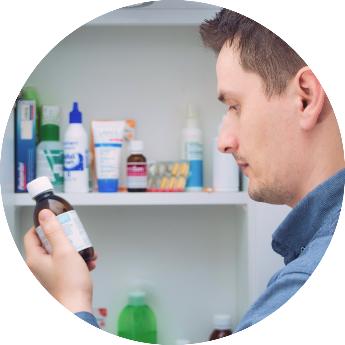 Man looking at bottle in front of open medicine cabinet
